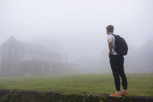 Teenager Walking Home Across Grass Lawn Covered In Cloud Mist 