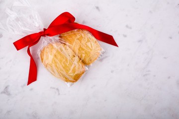 Madeleines wrapped with red ribbon on a white pastry board.