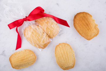 Madeleines wrapped with red ribbon on a white pastry board.