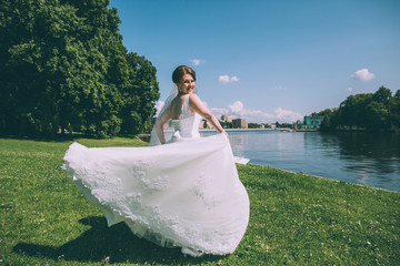Beautiful young bride in a magnificent wedding dress spinning in nature, happiness, fun