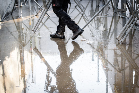 Construction site under water. Legs of a working man and his reflection in the water. Selective focus.