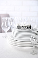 Clean plates, glasses and cutlery on white table