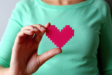 Closeup of plastic puzzle heart in female hand