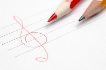 White paper sheet with two pencils and hand drawn stave and treble clef shallow depth of field have place for text