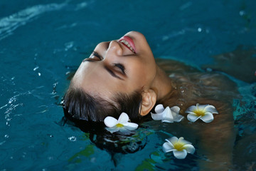 Beautiful young woman with flowers at swimming pool - Powered by Adobe