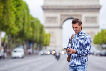 Young caucasian man holding a phone on the Champs Elysees in Paris
