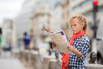 Adorable little girl with map of european city outdoors