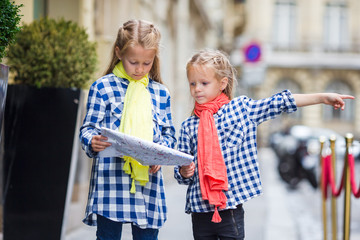 Adorable little girls with map of european city outdoors