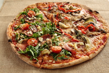 homemade pizza with arugula and tomato plant on a cloth sack
