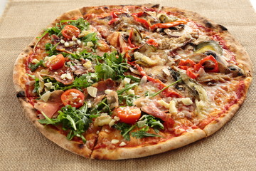 homemade pizza with arugula and tomato plant on a cloth sack
