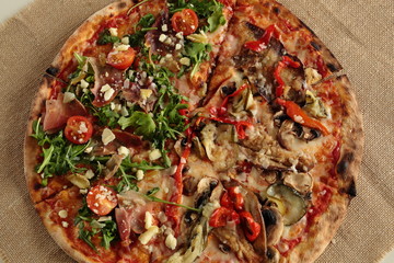 homemade pizza with arugula and tomato plant on a cloth sack
