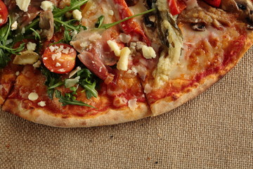 homemade pizza with arugula and tomato plant on a cloth sack
