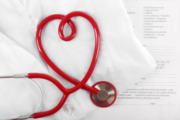 Red stethoscope, medical record and uniform, close up