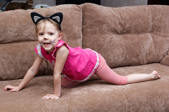 little girl with cat face painting on couch
