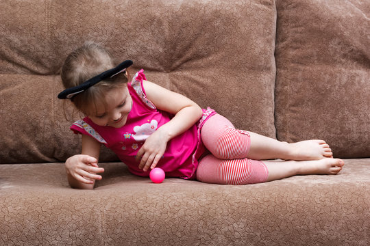 little girl with cat face painting play ball on couch