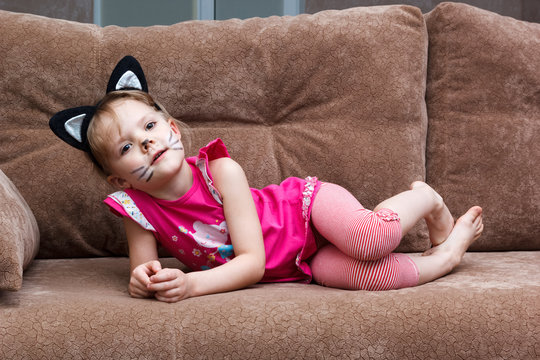 little girl with cat face painting on couch