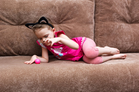little girl with cat face painting play ball on couch