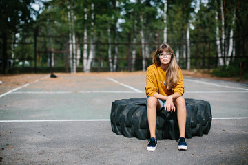 Beautiful hipster girl sitting on the wheel of the truck