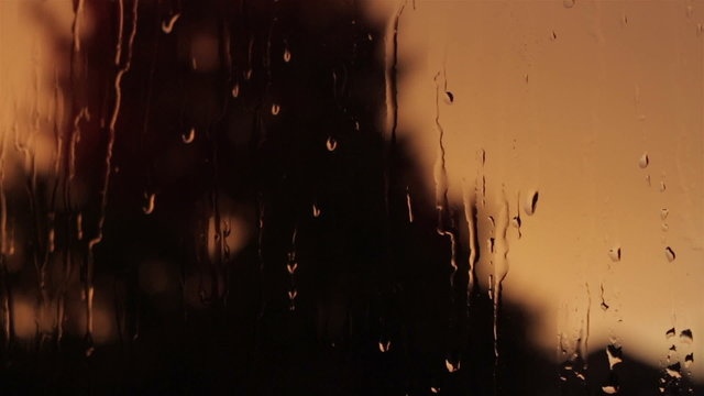 Closeup of fall rain on a window pane dark orange background