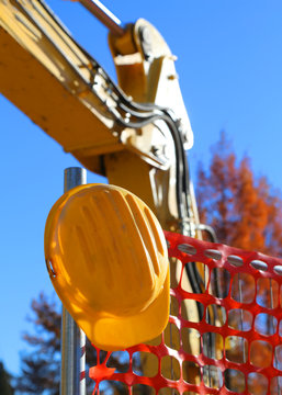 yellow hard hat on the road construction site and an excavator