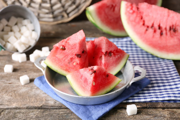 Sliced watermelon in metal bowl on decorated wooden background