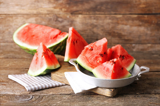 Sliced watermelon in metal bowl on wooden background