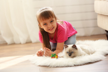 Little cute girl playing with kitten at home