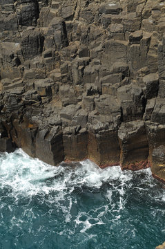 Waves crashing on basalt cliffs.