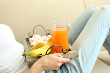 A girl with a tray having lunch on a sofa, close-up
