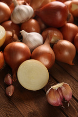 Fresh onions with garlic on wooden background