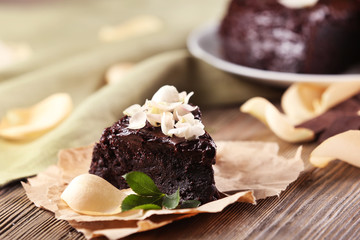 Piece of chocolate cake decorated with flowers on brown wooden table