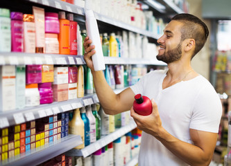 Man chooses shampoo in store