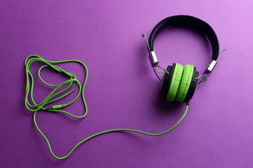 A pair of green-black headphones, on purple background