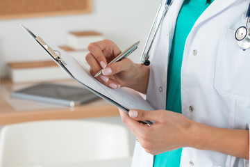 Close-up view of female doctor hands filling patient registratio