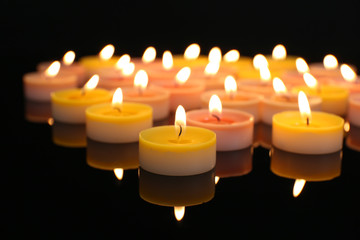 Many burning small candles on dark background