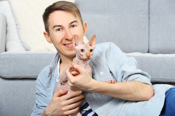 Young handsome man lies with cat on floor at home