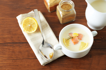 Delicious salmon cream soup on wooden table, which served with sliced lemon and spices