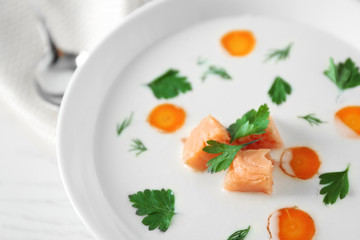 Delicious cream soup with salmon and carrot in white bowl