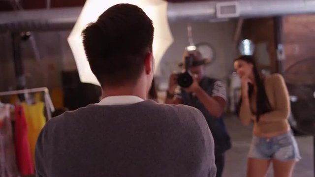 Over the shoulder shot of Male model as photographer asks stylist assistant to make changes