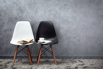 Stylish conception with white and black chairs on grey background