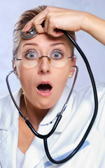 Shocked female doctor listening her mind with stethoscope.