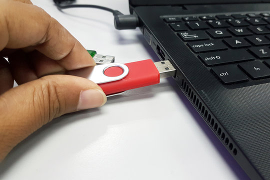 Close up of a woman hand plugging a pendrive on a laptop in soft focus