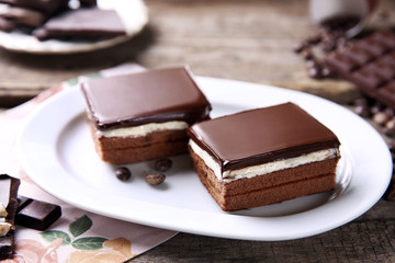 Delicious chocolate brownies on plate, on wooden background