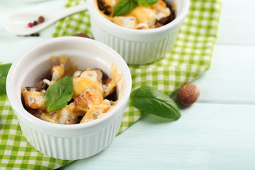 French dish julienne. Mushroom, chicken and cheese gratin in ceramic bowls, on wooden background