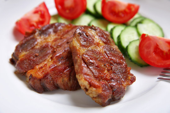 Roasted beef fillet and fresh vegetables on plate, on wooden background