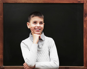 Young cute schoolboy posing at the blackboard