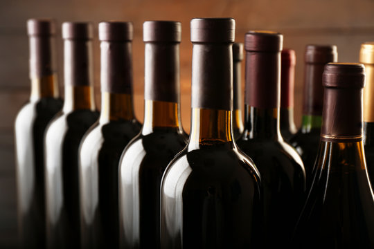 Wine bottles in a row on wooden background, close up