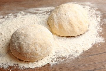 Dough balls for pizza on floured wooden board