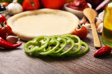 Dough basis and ingredients for pizza, on the table