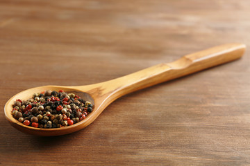 Wooden spoon with pepper on the table, close-up